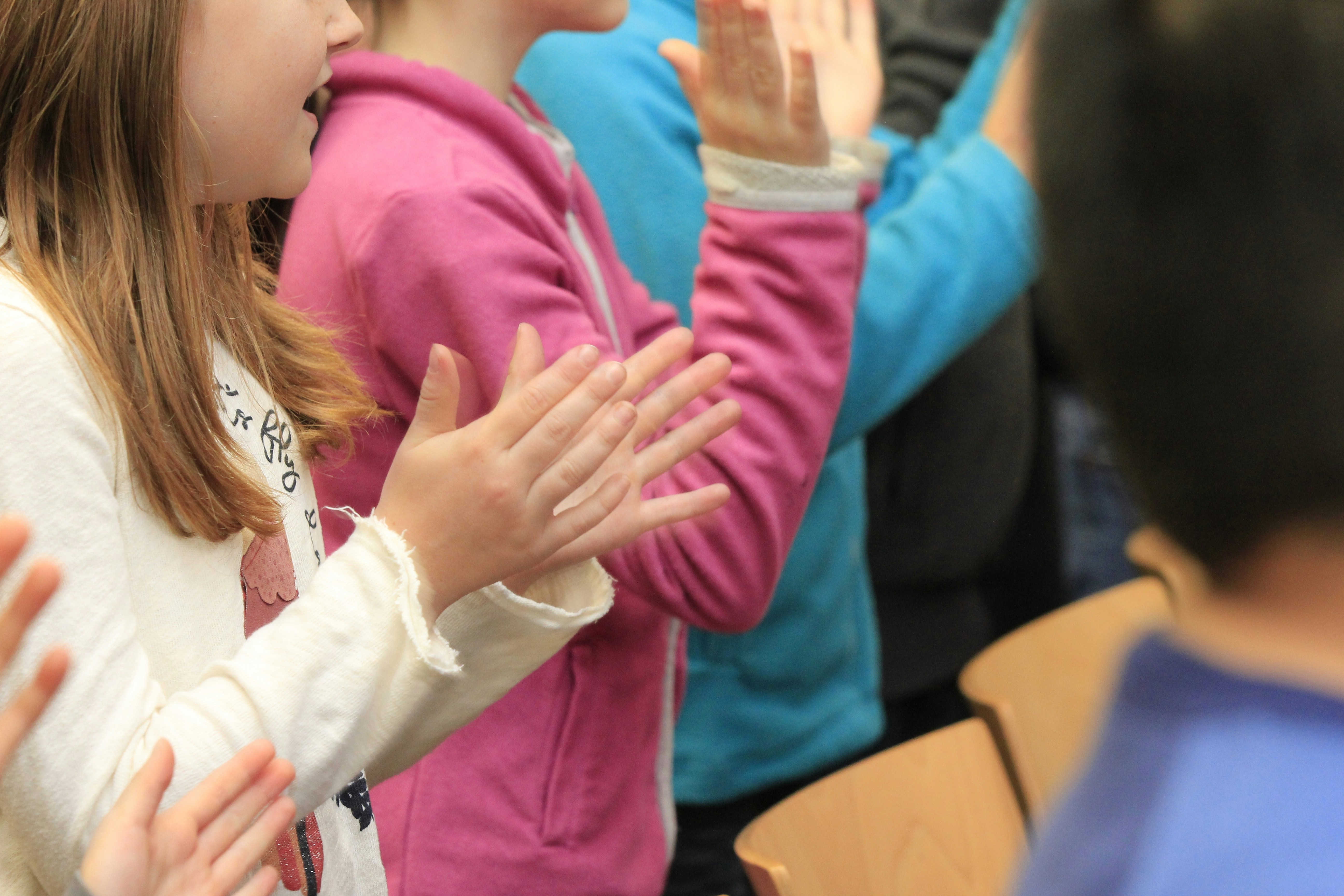 A group of children clapping in a classroom