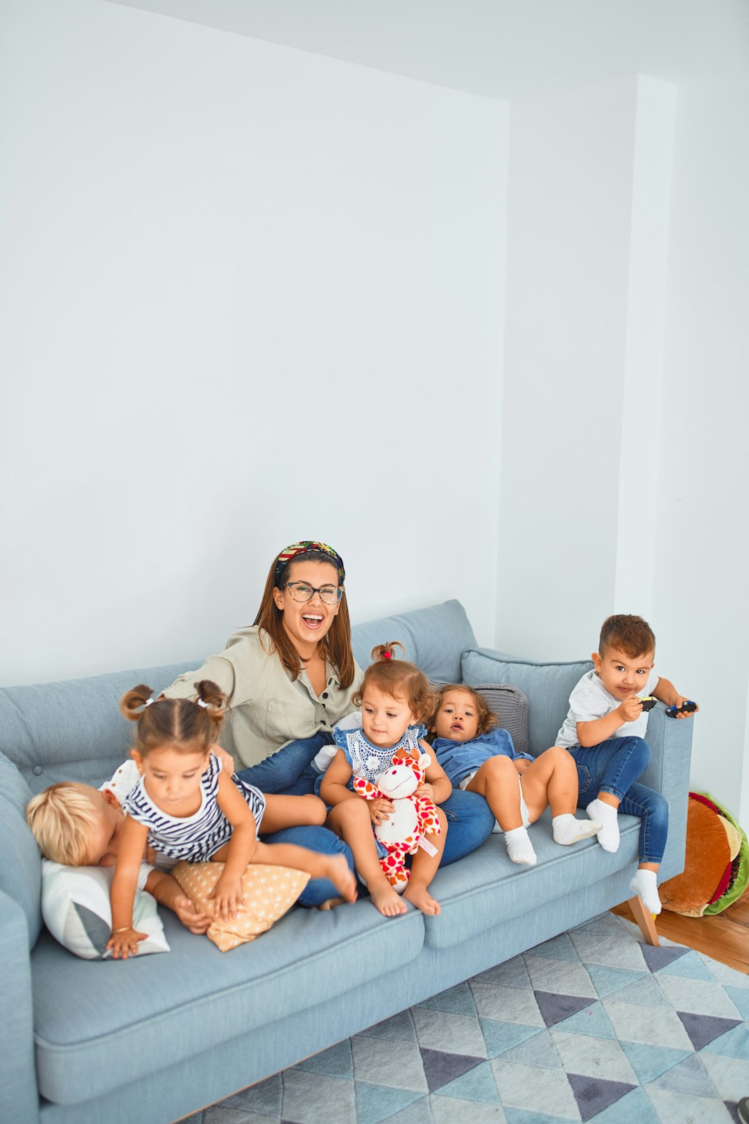 Beautiful teacher and group of toddlers sitting on the sofa playing at kindergarten by School Play Scripts 3 women sitting on gray couch