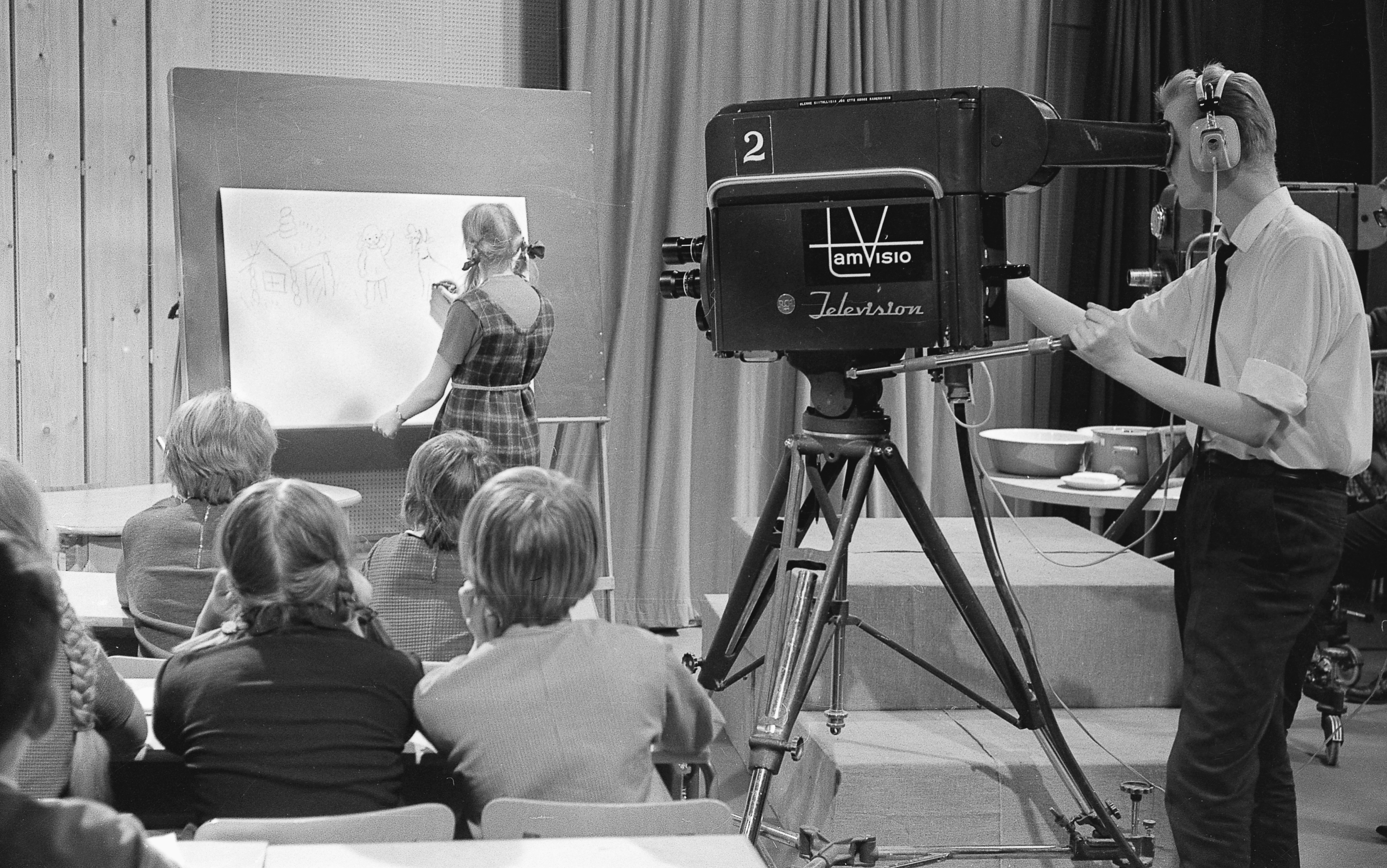 a man standing in front of a camera in front of a group of people