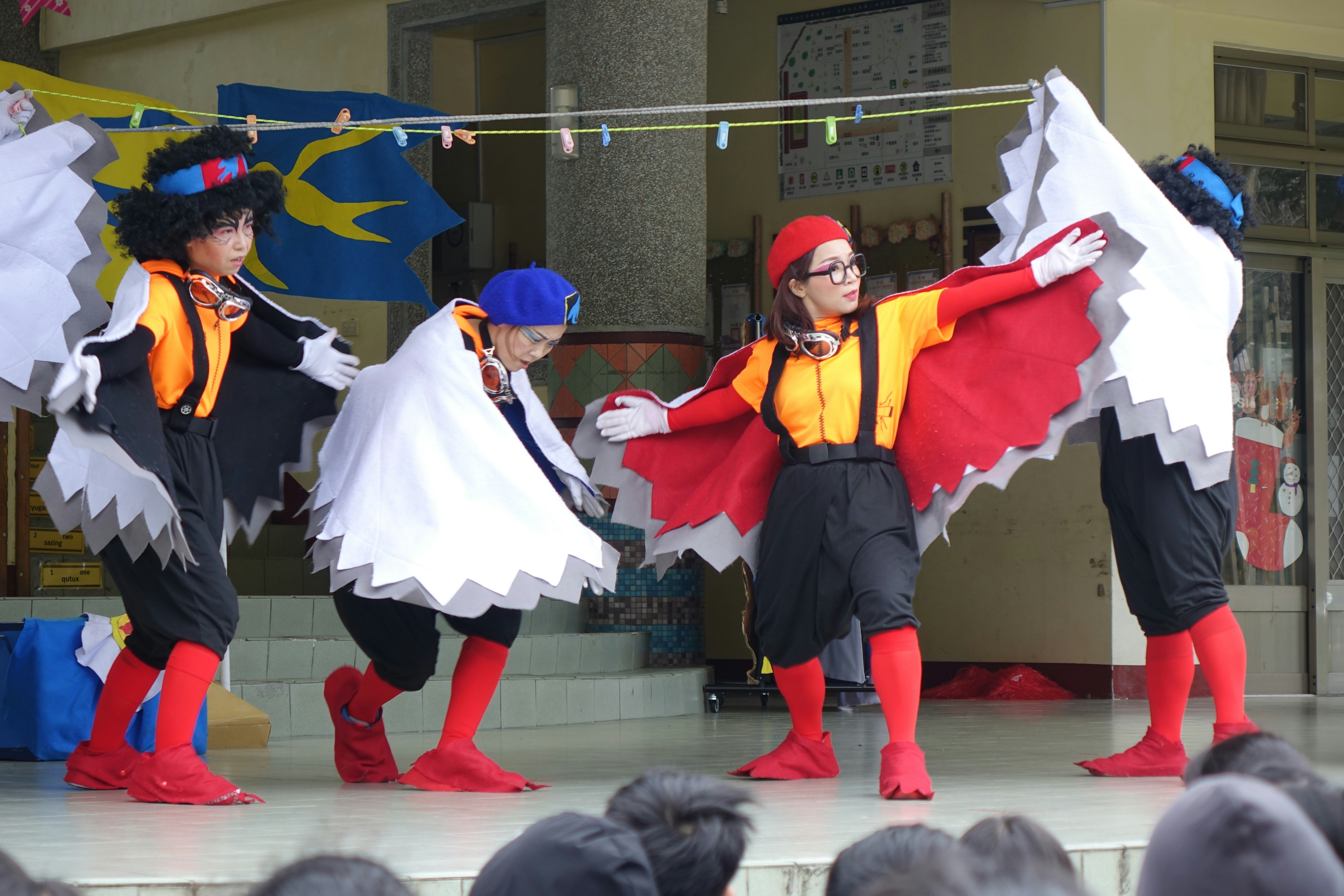 Children dressed as birds perform on stage.