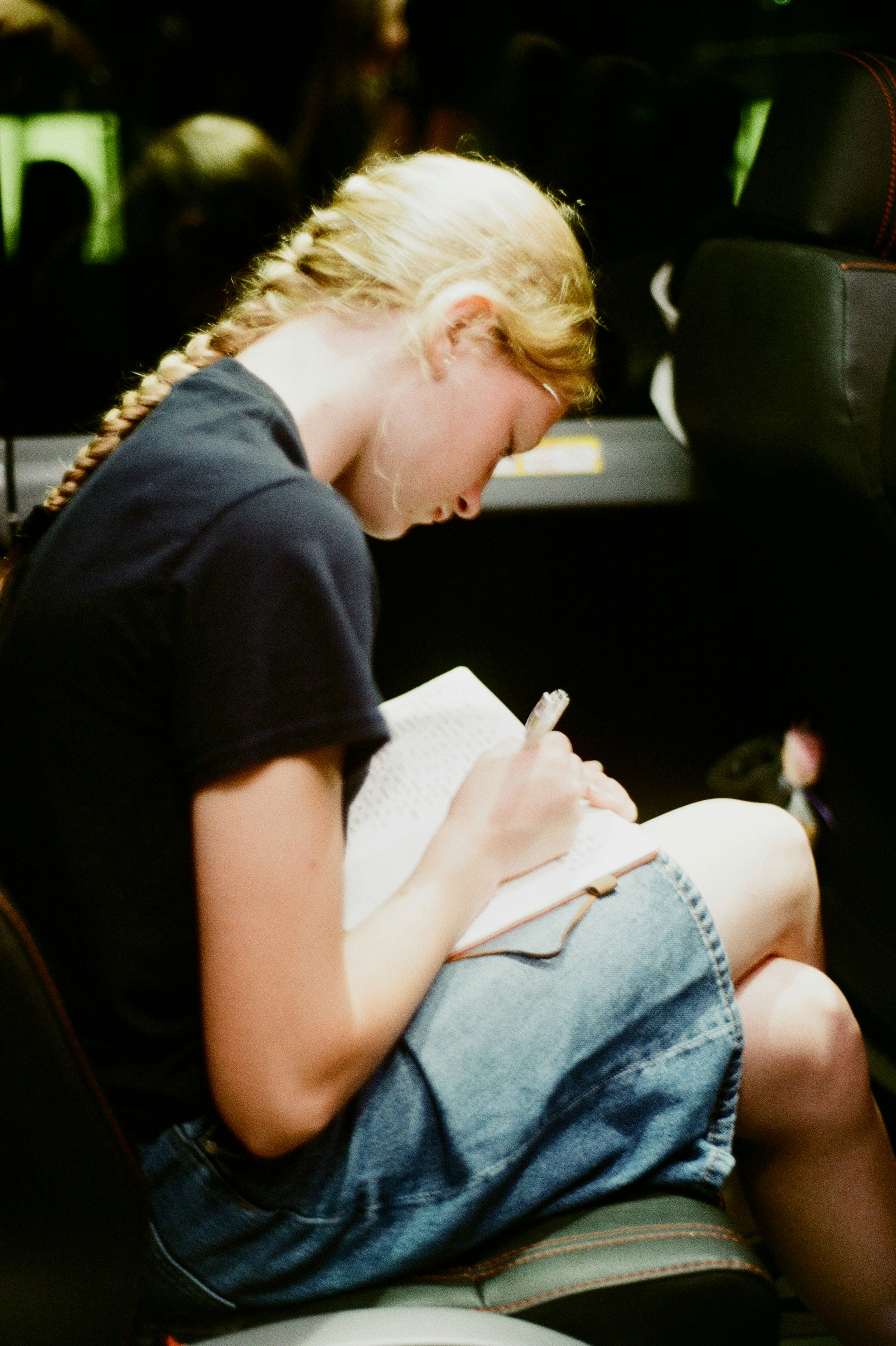 A young woman is writing in a notebook.