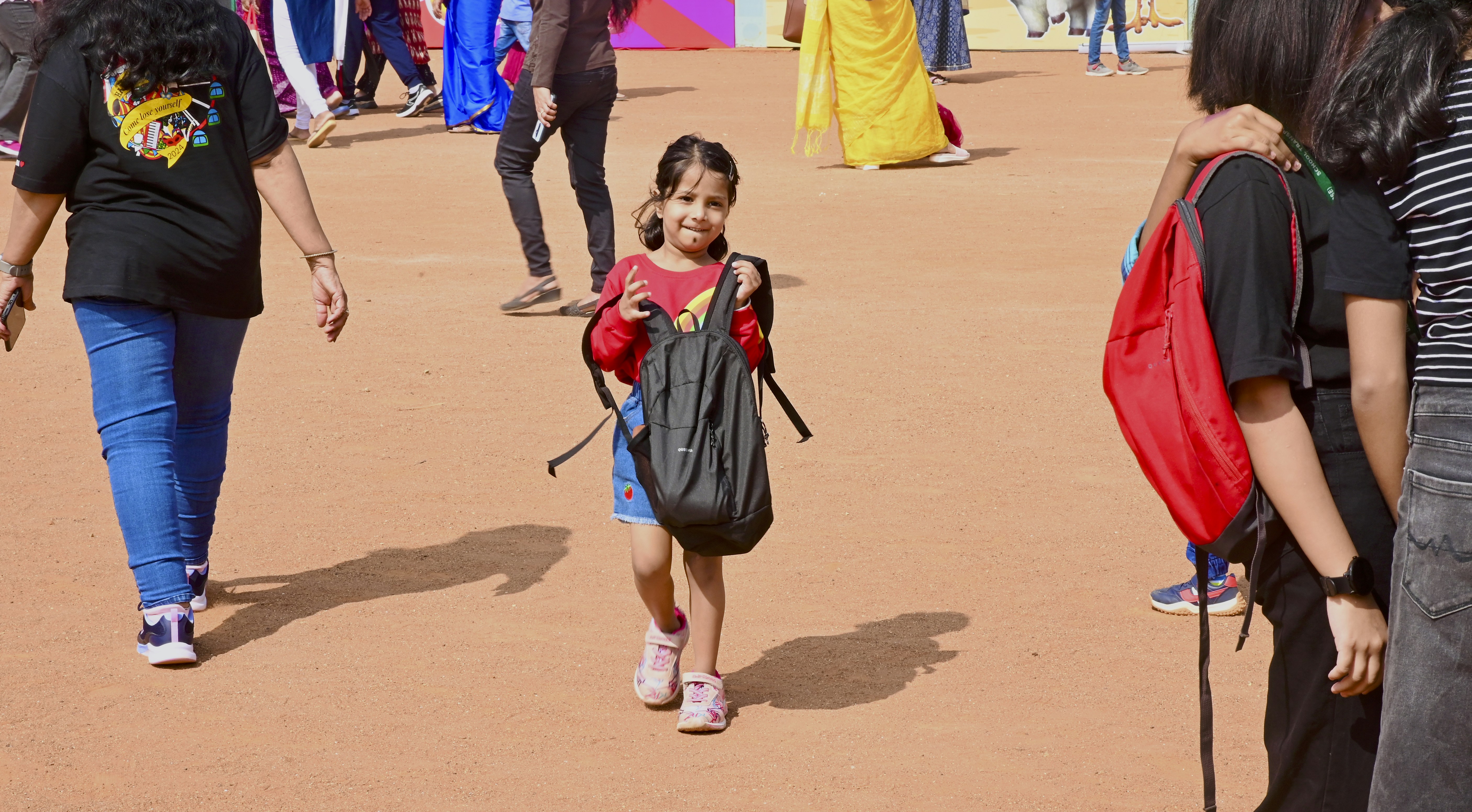 A young girl with a backpack walks outside.