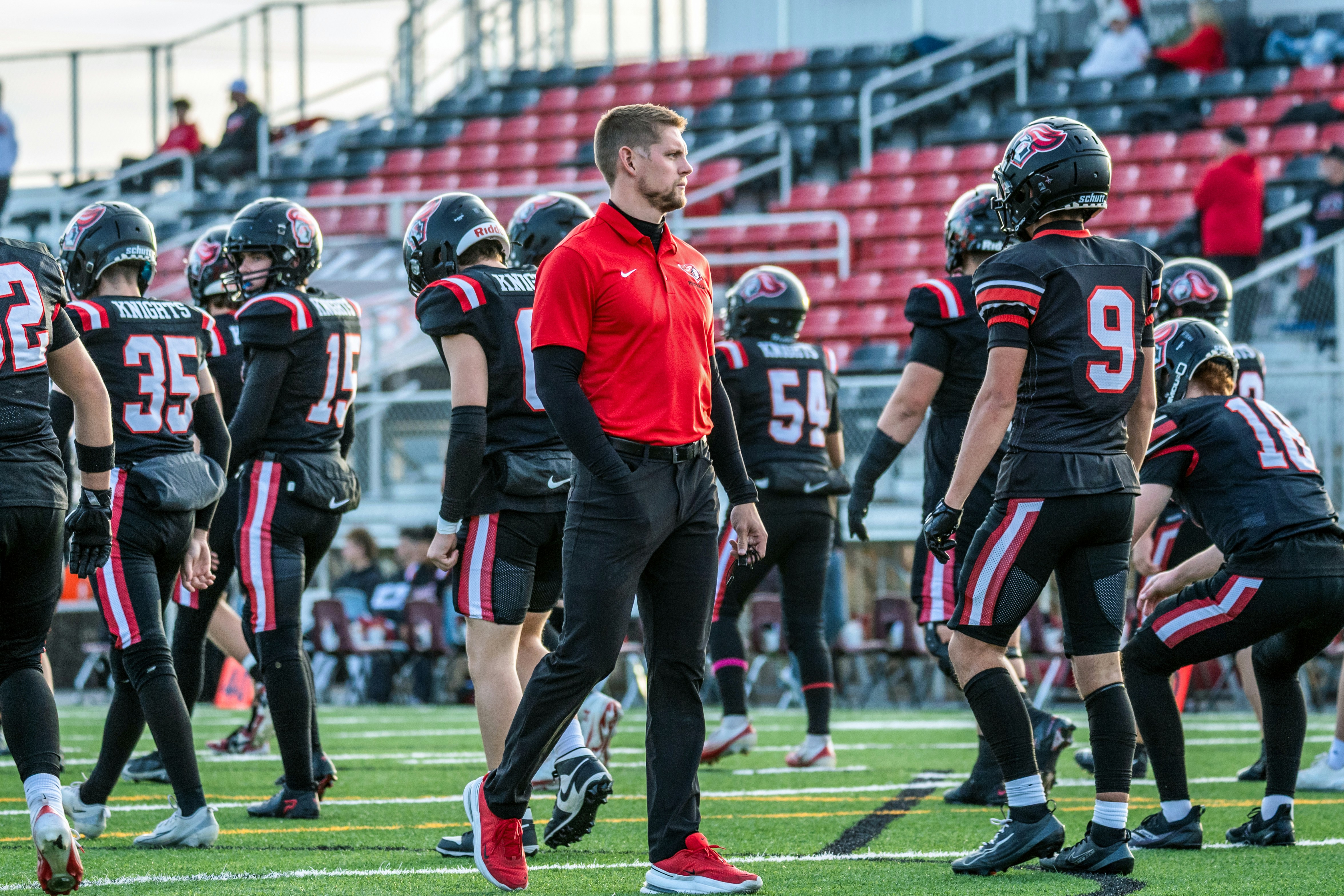 Coach watches football players on the field.