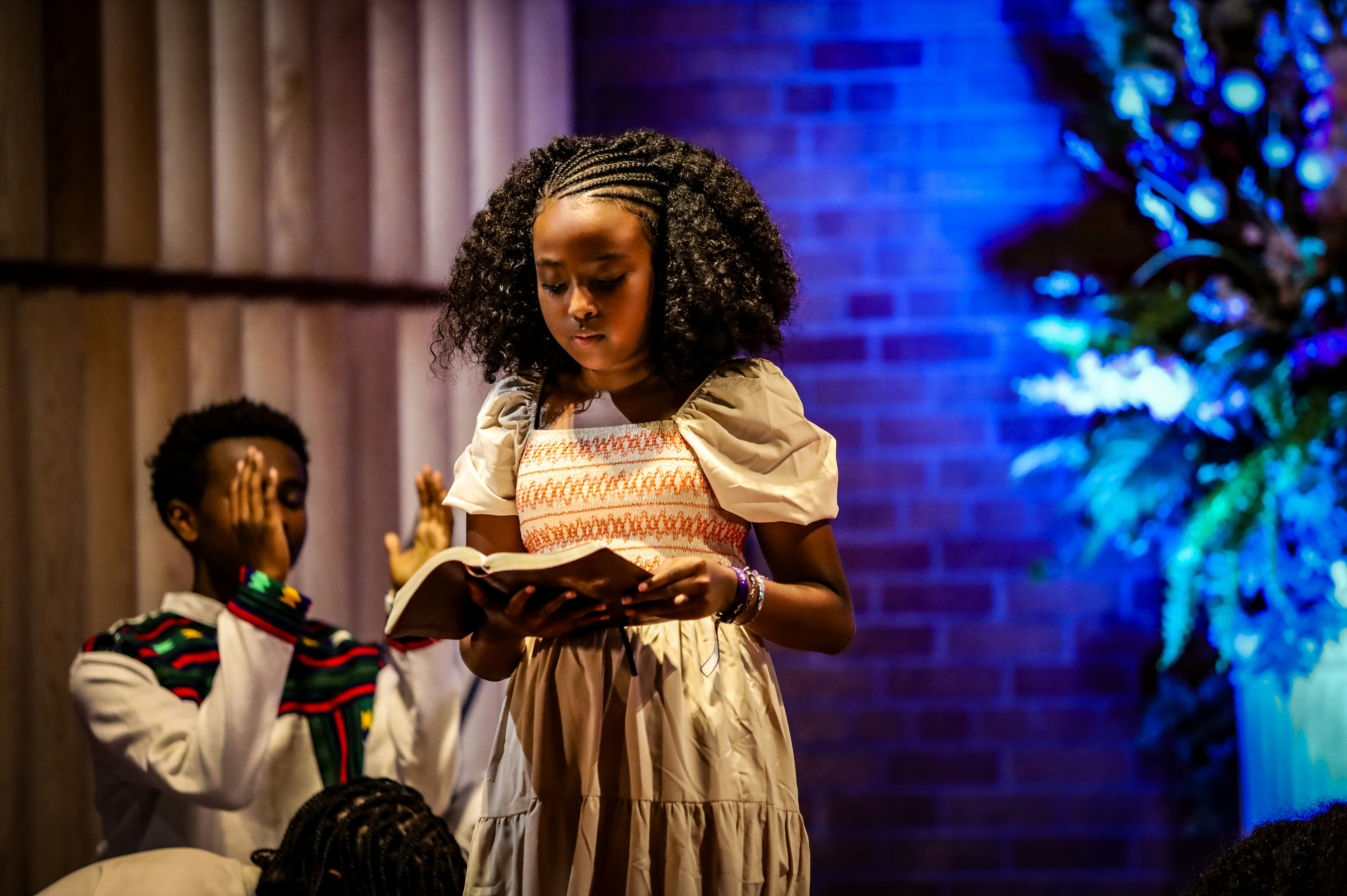 A young girl reads a book on stage.