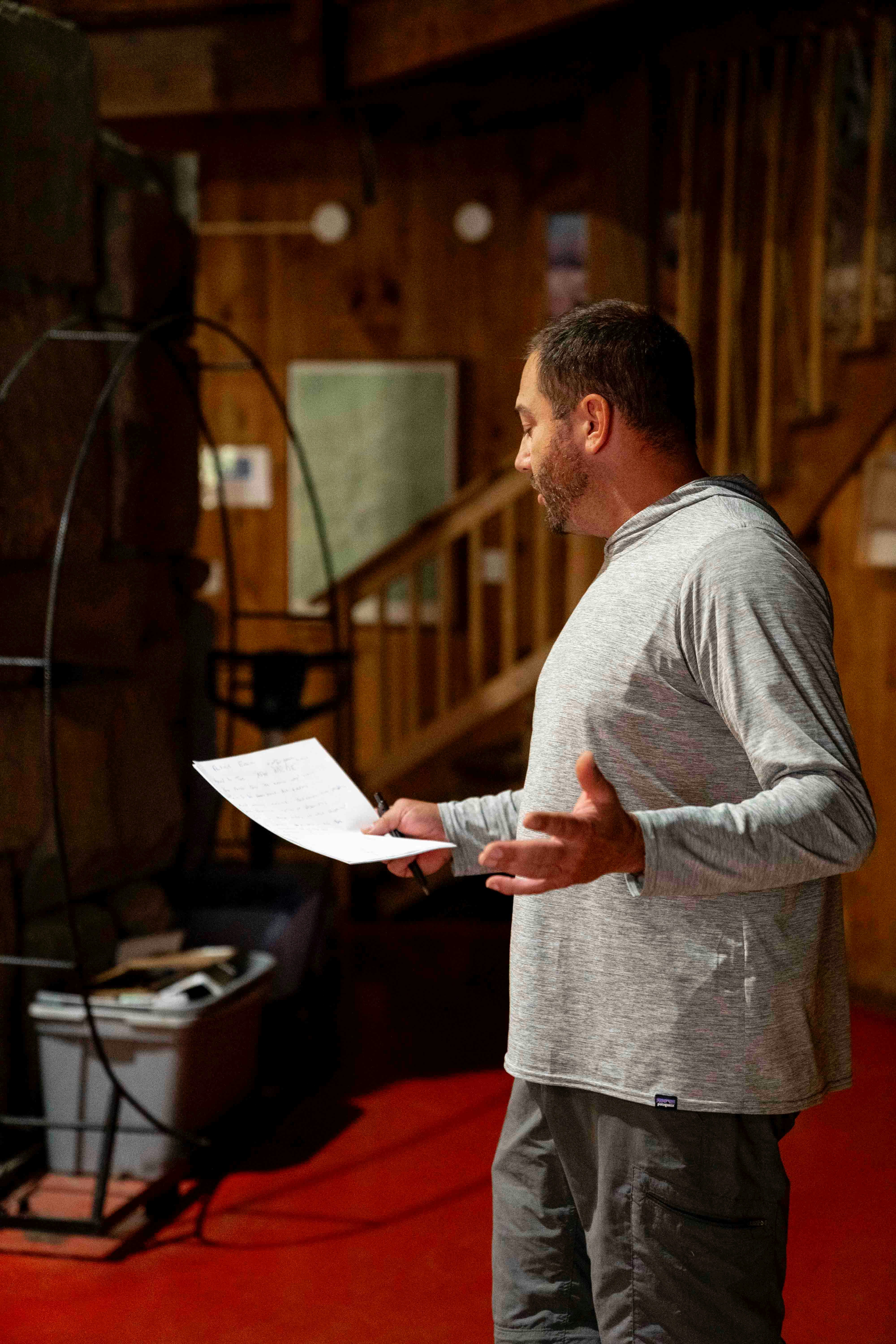 Man holding paper and gesturing while speaking indoors