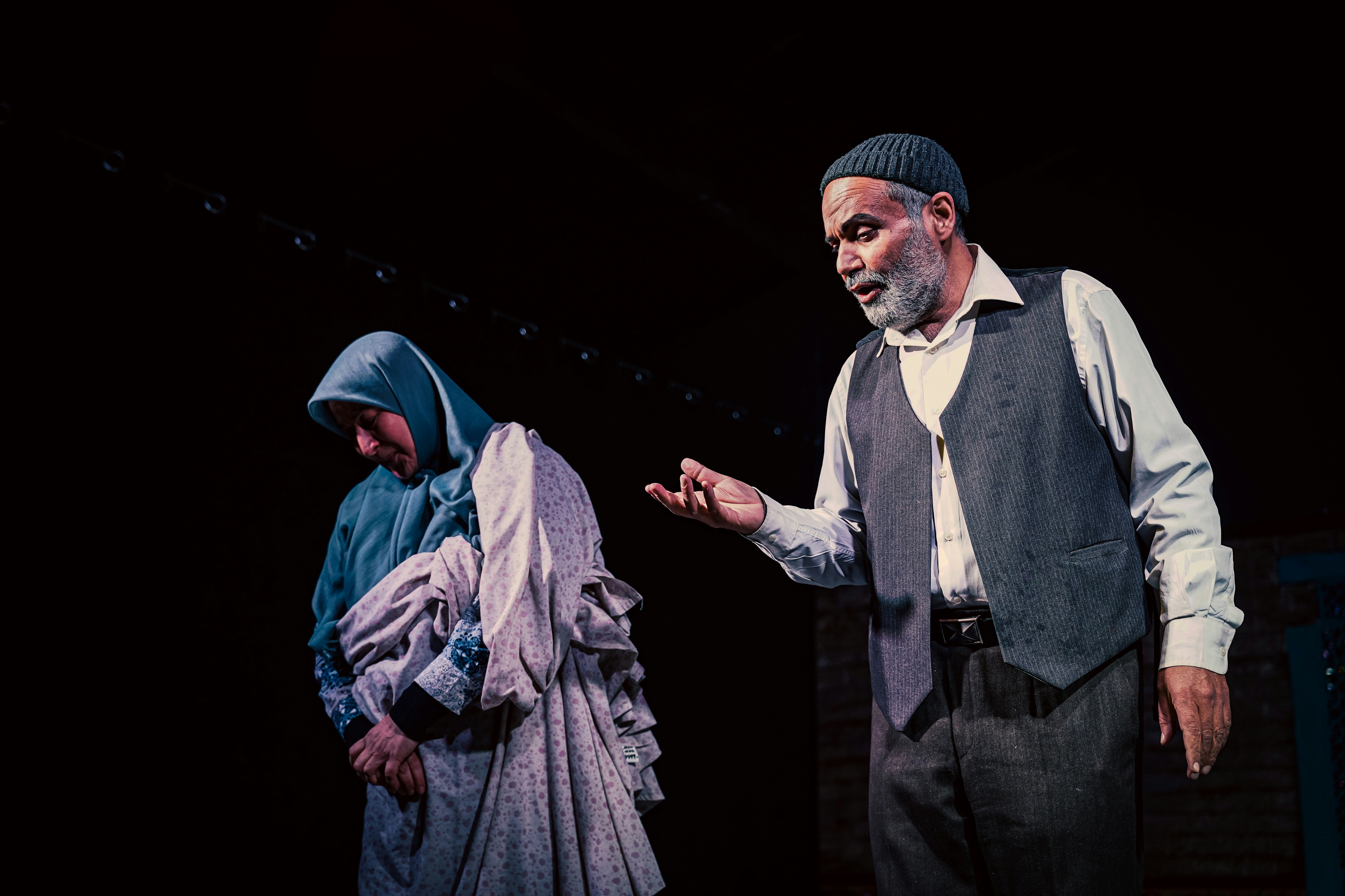 Elderly couple in traditional clothing on stage.