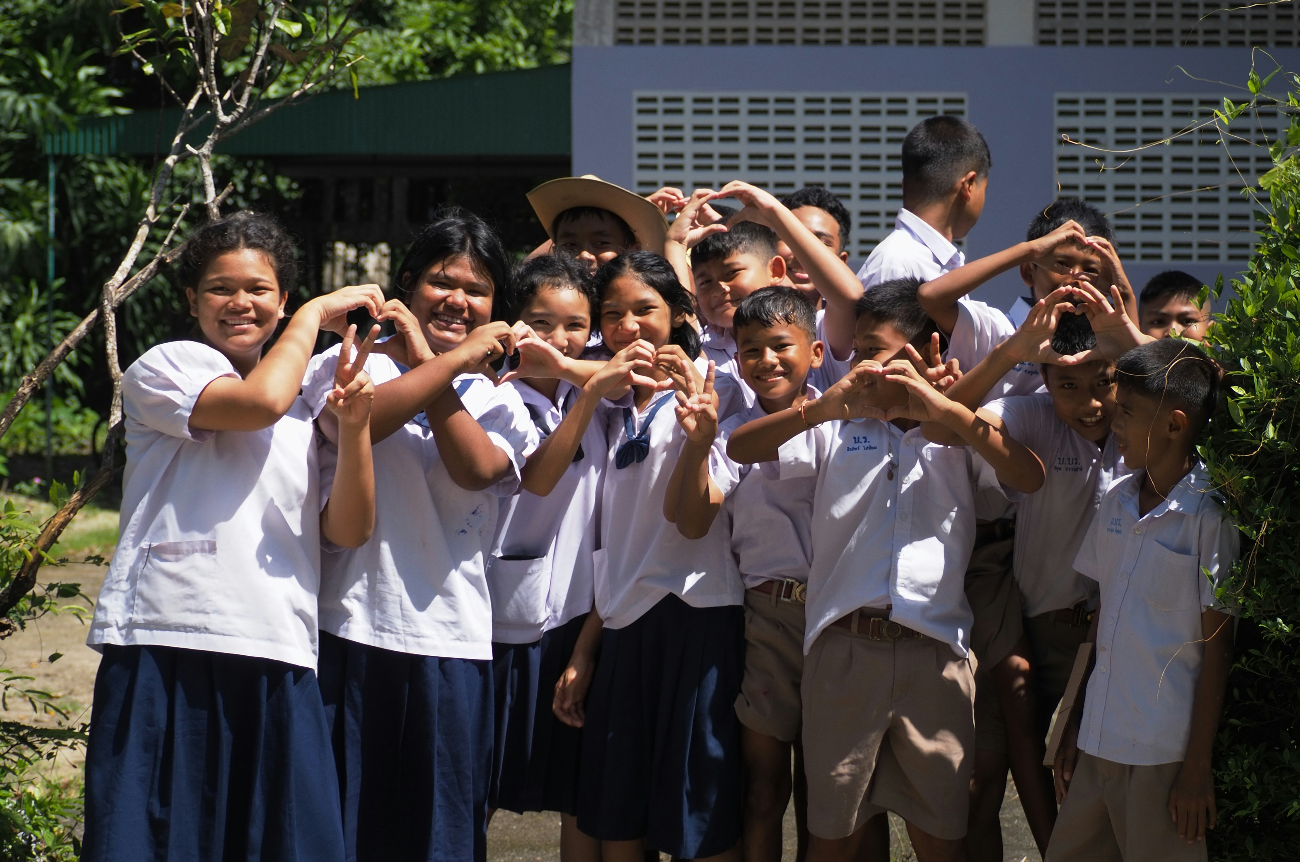 Children in uniform make heart shapes with hands
