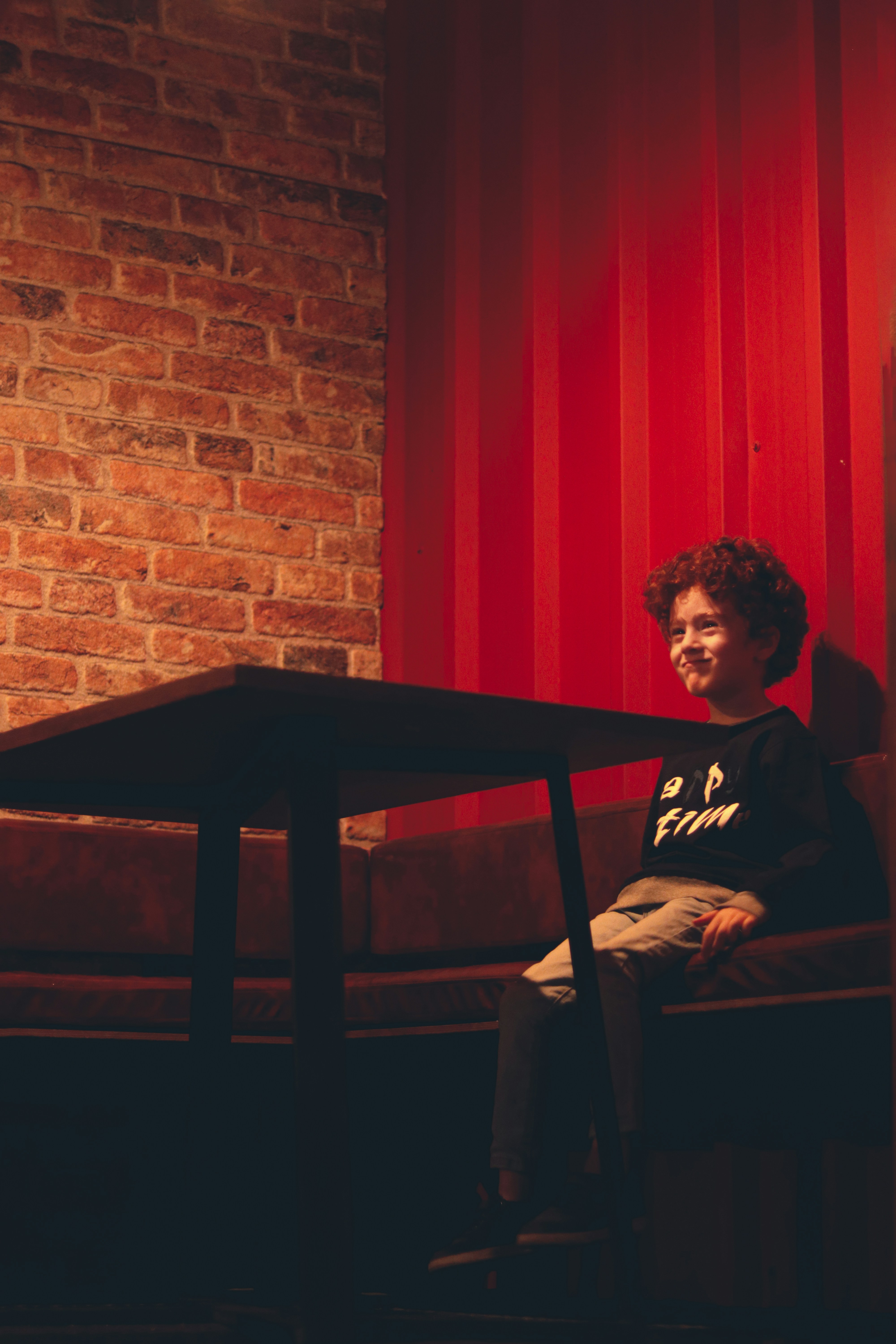 a man sitting at a table in front of a red brick wall