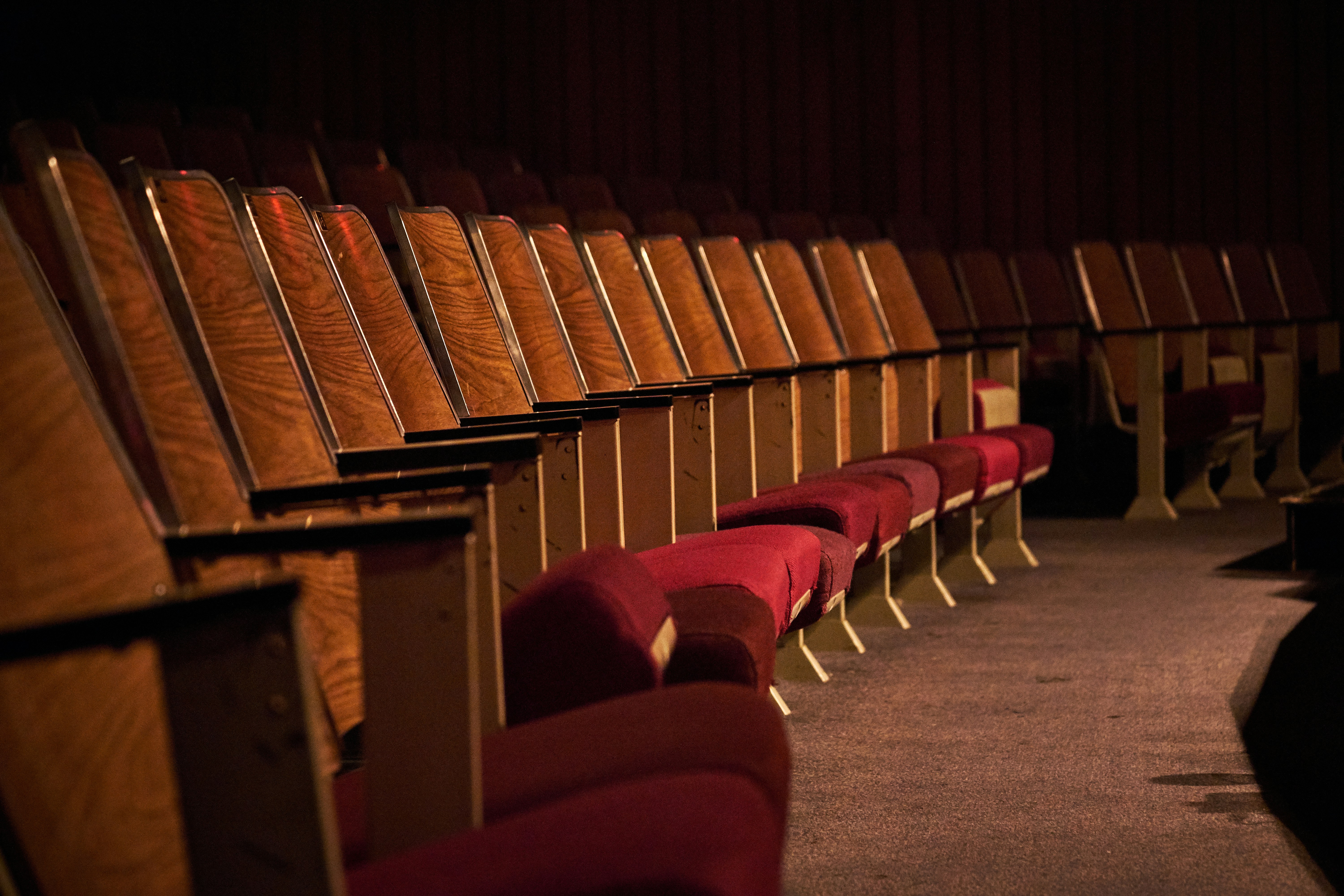 Red seats at an auditorium. by School Play Scripts brown wooden chairs on gray carpet