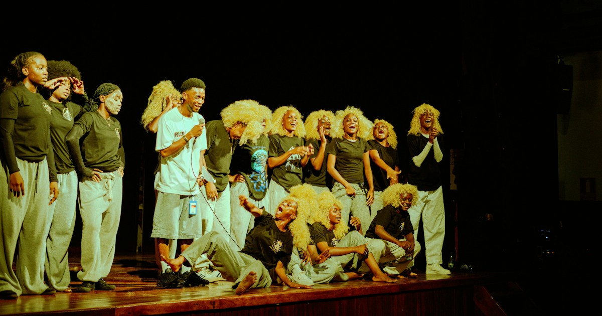 A group of performers in black shirts and grey pants on a stage